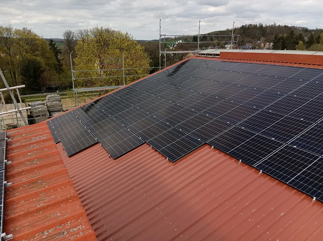 Photovoltaic panels installed on a red industrial roof